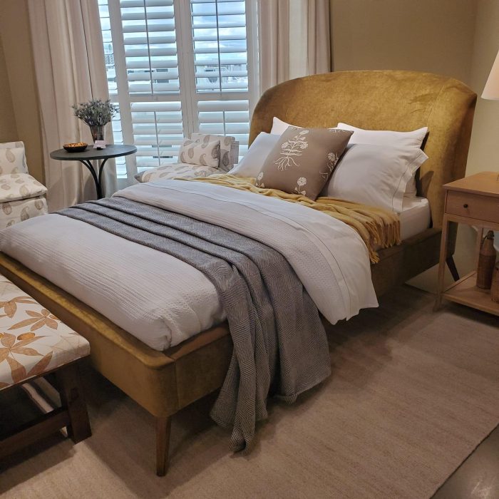 A cozy bedroom featuring a comfortable bed with soft pillows and a warm duvet, soft lighting, and perhaps a bedside table